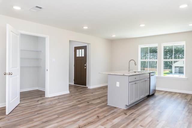 kitchen with gray cabinetry, sink, a center island with sink, and light hardwood / wood-style flooring