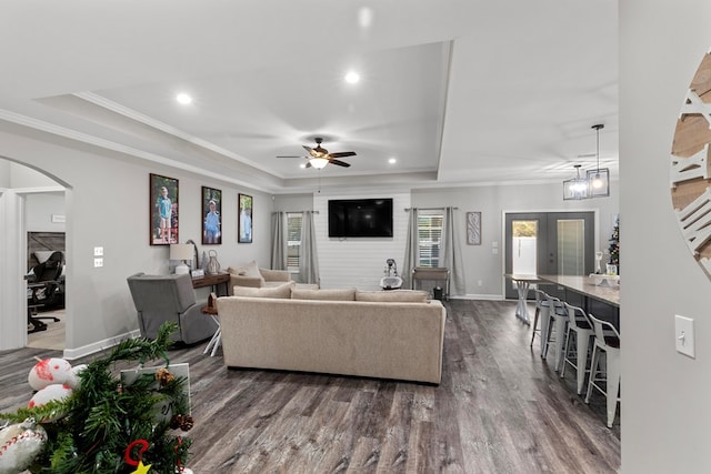 living room featuring a raised ceiling, crown molding, french doors, and dark wood-type flooring