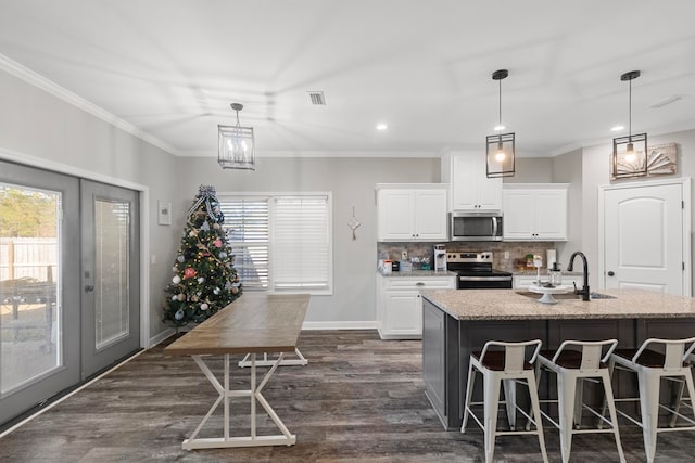 kitchen with white cabinets, plenty of natural light, stainless steel appliances, and an island with sink