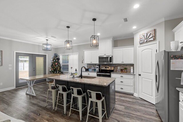 kitchen with white cabinets, sink, stainless steel appliances, and an island with sink