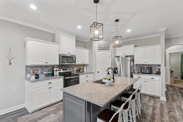 kitchen with a center island with sink, a breakfast bar, white cabinetry, and appliances with stainless steel finishes