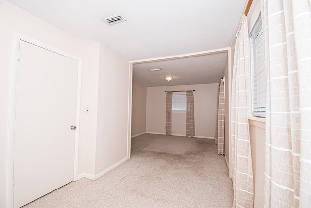 hallway with visible vents, baseboards, and carpet flooring