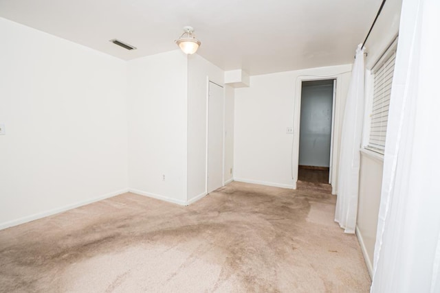 unfurnished room with light carpet, visible vents, and baseboards