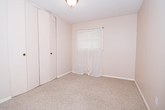 unfurnished bedroom featuring a closet, baseboards, and carpet floors