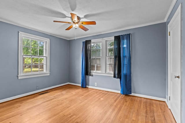 unfurnished room with healthy amount of natural light, wood finished floors, ceiling fan, baseboards, and crown molding