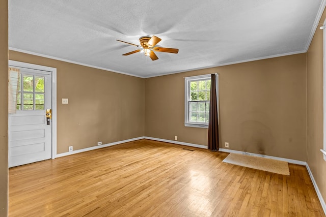 unfurnished room featuring a ceiling fan, plenty of natural light, light wood-style floors, baseboards, and crown molding