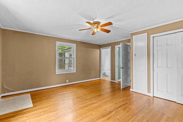 unfurnished bedroom featuring light wood-type flooring, ornamental molding, baseboards, a textured ceiling, and ensuite bathroom