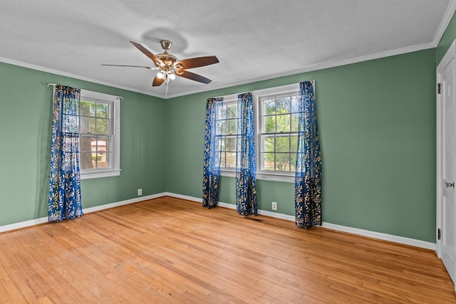 unfurnished room with wood finished floors, ceiling fan, ornamental molding, baseboards, and a textured ceiling