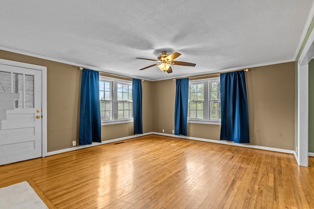 empty room featuring ceiling fan, healthy amount of natural light, baseboards, a textured ceiling, and crown molding