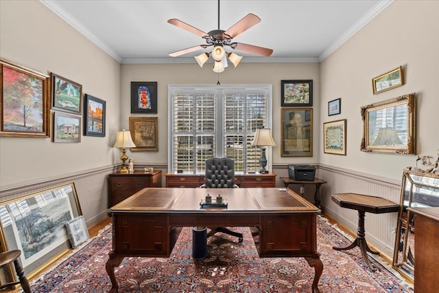 home office with ornamental molding, a wainscoted wall, ceiling fan, and wood finished floors