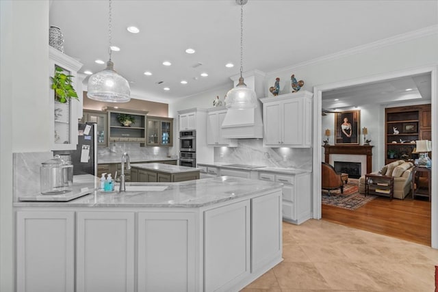 kitchen featuring stainless steel appliances, a fireplace, a sink, white cabinetry, and ornamental molding