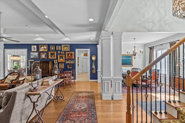 interior space featuring decorative columns, stairway, light wood-style flooring, and a notable chandelier