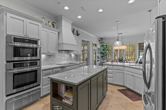 kitchen featuring a warming drawer, custom exhaust hood, stainless steel appliances, decorative backsplash, and a kitchen island