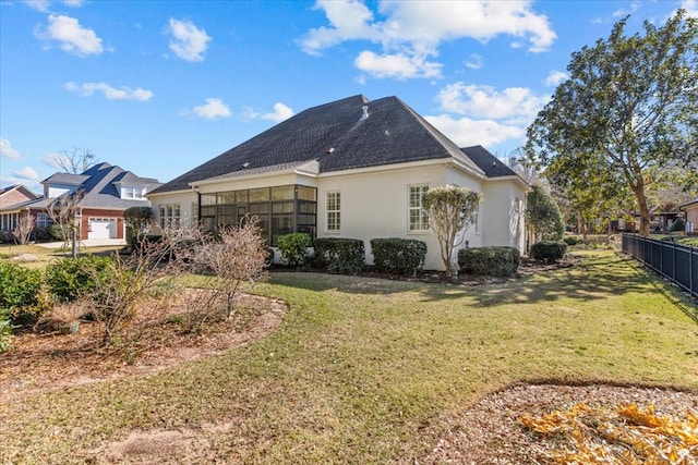 rear view of property featuring a yard, a sunroom, and fence