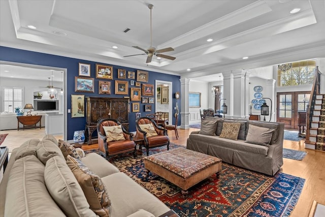 living area with a healthy amount of sunlight, light wood finished floors, decorative columns, and a raised ceiling