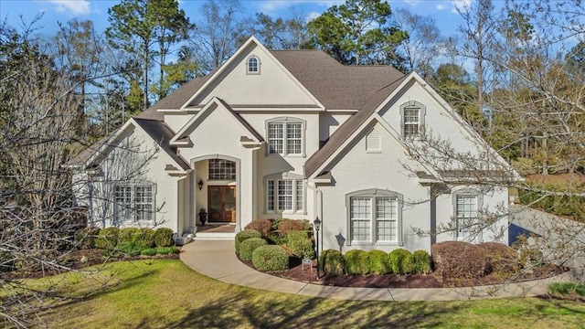 french country inspired facade with brick siding and a front lawn