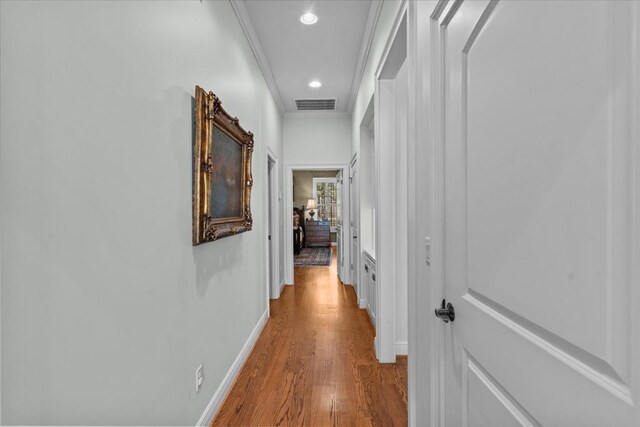 hallway with crown molding, recessed lighting, visible vents, wood finished floors, and baseboards