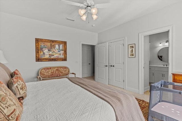 bedroom featuring light carpet, ensuite bath, a ceiling fan, and a closet