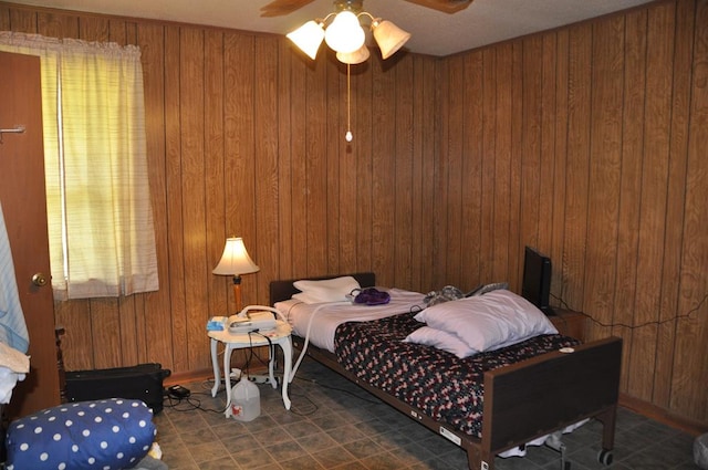 bedroom with ceiling fan and wood walls