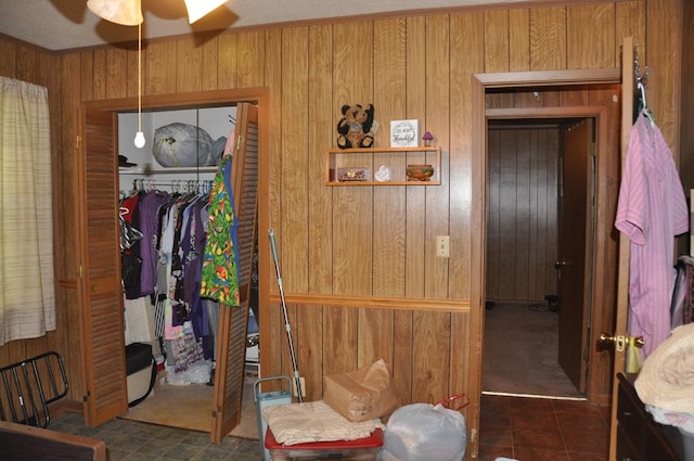 bedroom with ceiling fan, a closet, and wood walls