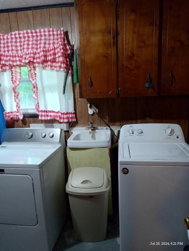 clothes washing area featuring cabinets, sink, and washing machine and clothes dryer