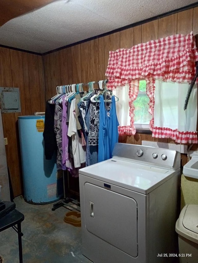 clothes washing area featuring washer / dryer, a textured ceiling, gas water heater, and wooden walls