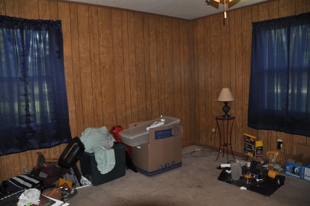 miscellaneous room featuring carpet flooring, ceiling fan, and wooden walls