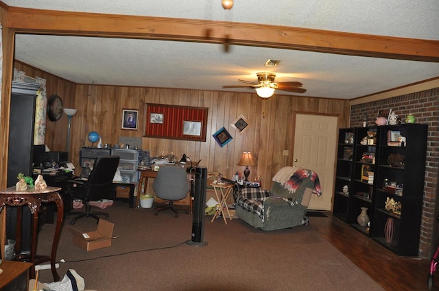 home office with brick wall, a textured ceiling, ceiling fan, carpet floors, and wood walls