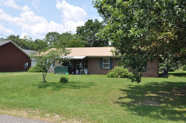 210 Anderson St, Kinston, AL 36453 - view of front facade featuring a front yard, brick siding, and a metal roof