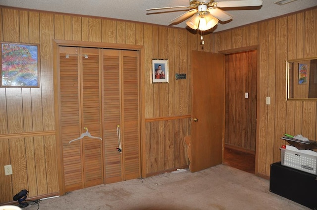 bedroom with ceiling fan, wood walls, and light colored carpet