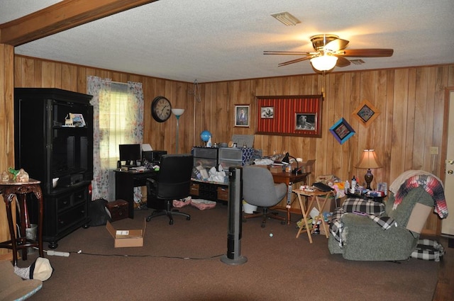 carpeted office space with ceiling fan, a textured ceiling, and wooden walls