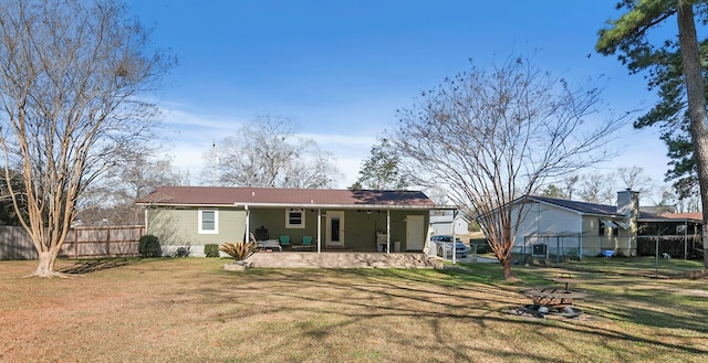 back of house featuring a fire pit, fence, a lawn, and a patio