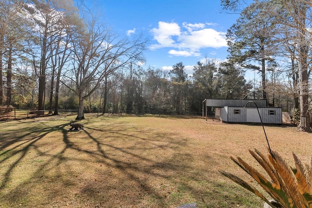 view of yard featuring an outbuilding, a shed, and fence