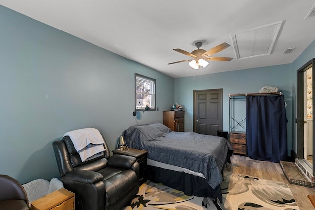 bedroom with visible vents, ceiling fan, light wood-style flooring, and attic access