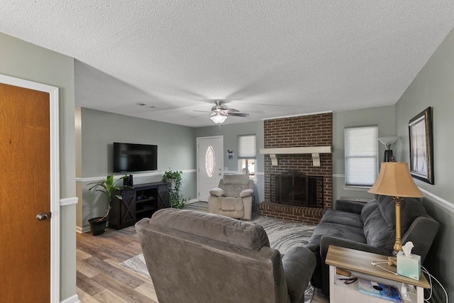 living room with plenty of natural light, a fireplace, visible vents, and wood finished floors