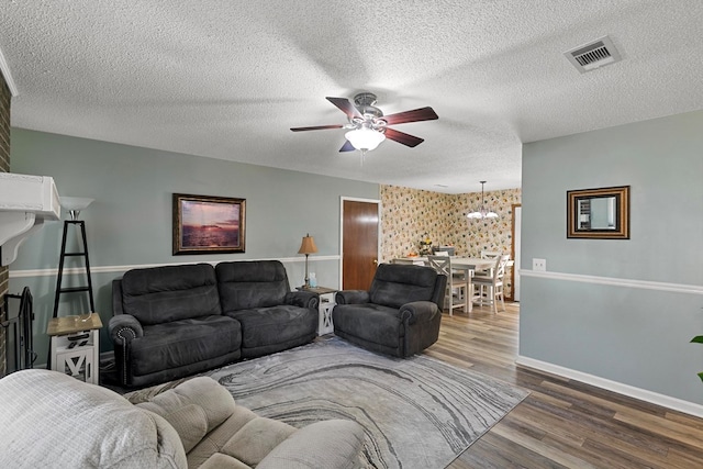 living room featuring baseboards, visible vents, a ceiling fan, wood finished floors, and a textured ceiling