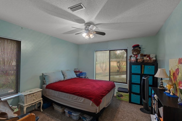 carpeted bedroom featuring ceiling fan, visible vents, and a textured ceiling