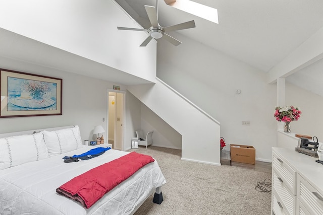 bedroom with light carpet, a skylight, baseboards, ceiling fan, and high vaulted ceiling