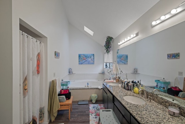 bathroom featuring double vanity, lofted ceiling, wood finished floors, a garden tub, and a sink