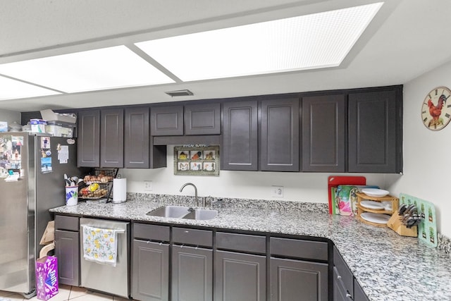 kitchen featuring light stone counters, stainless steel appliances, a sink, visible vents, and dark brown cabinets