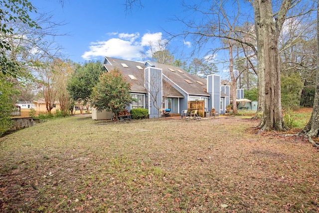 rear view of house featuring a chimney and a yard