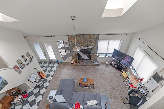 unfurnished living room featuring carpet floors, a stone fireplace, and a skylight