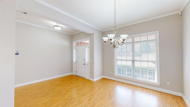 empty room featuring ornamental molding, hardwood / wood-style floors, and a chandelier