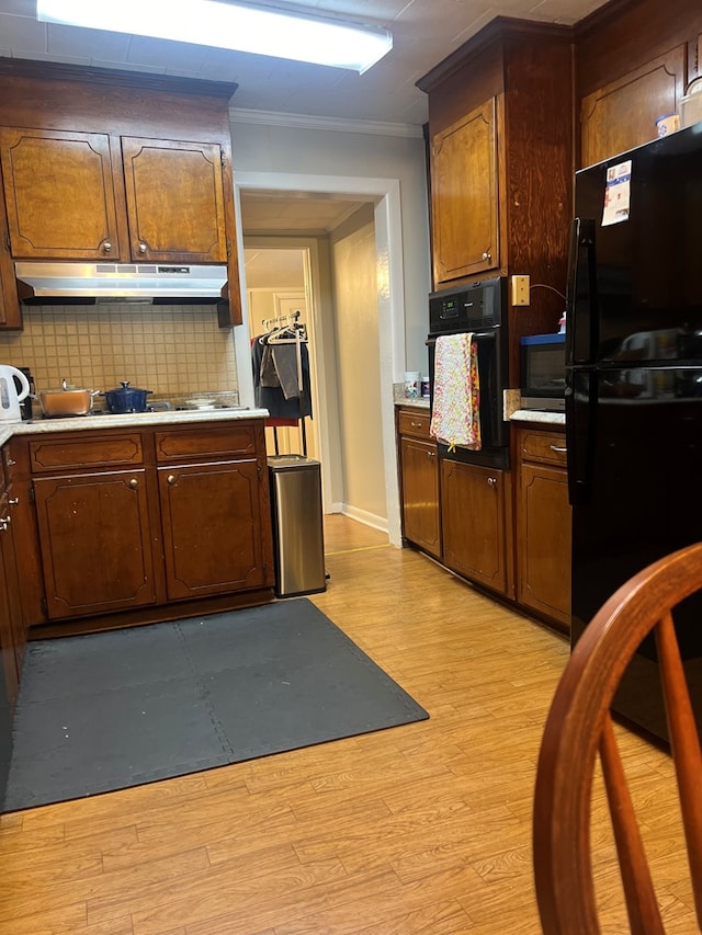 kitchen featuring tasteful backsplash, ornamental molding, black appliances, and light hardwood / wood-style floors