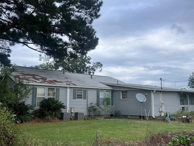 rear view of house featuring a lawn and cooling unit