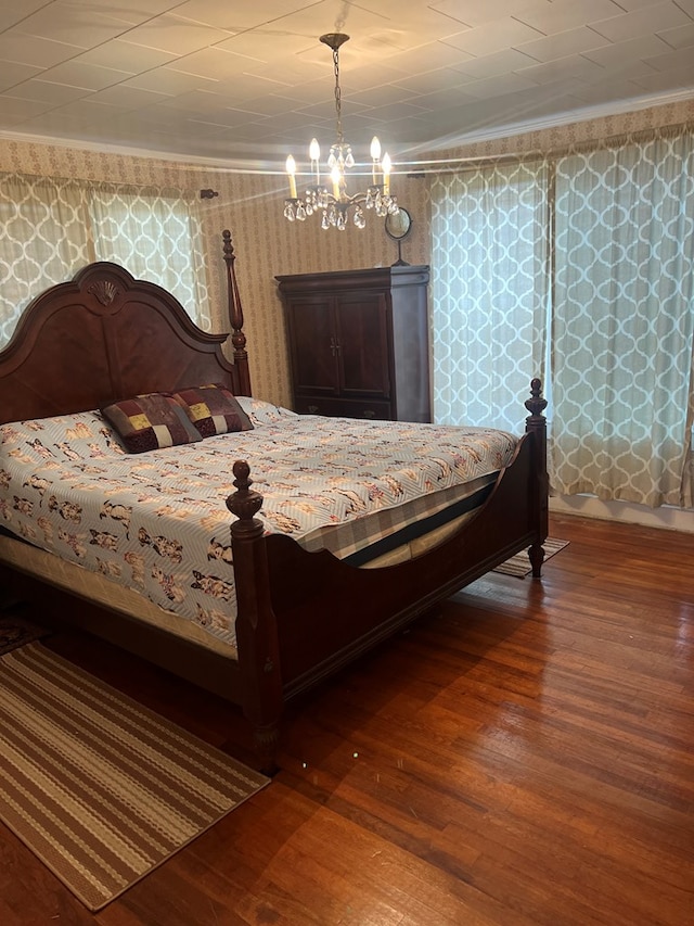 bedroom featuring hardwood / wood-style flooring, a notable chandelier, and crown molding