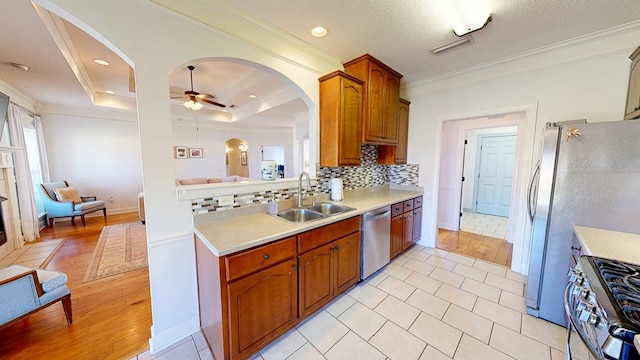 kitchen featuring ceiling fan, a sink, light countertops, appliances with stainless steel finishes, and ornamental molding