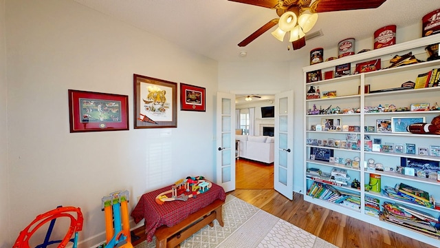 rec room featuring visible vents, a fireplace, a ceiling fan, and wood finished floors