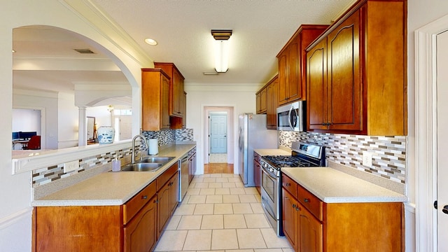 kitchen with ornamental molding, light countertops, appliances with stainless steel finishes, and a sink