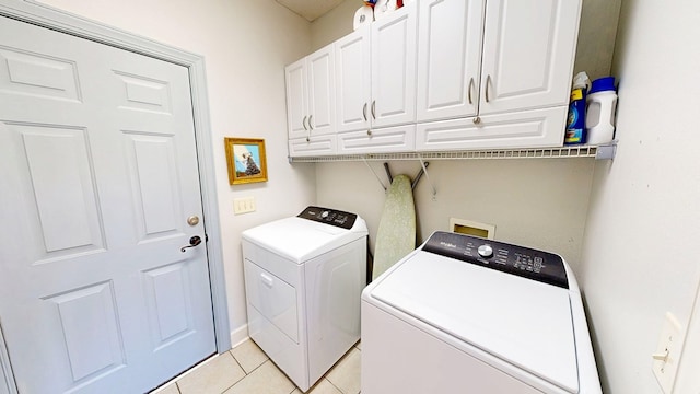 laundry area featuring light tile patterned floors, washer and clothes dryer, and cabinet space